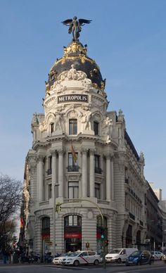 an ornate building on the corner of a street with cars parked in front of it