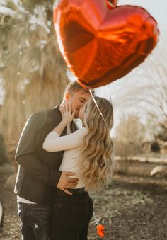 a man and woman kissing under a red heart balloon