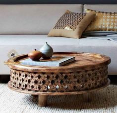 a coffee table sitting on top of a rug next to a white couch and pillows