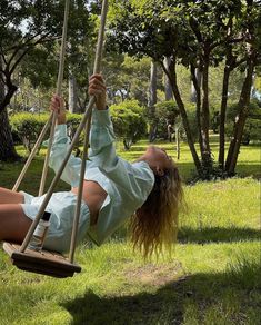 a woman is laying on a swing in the grass