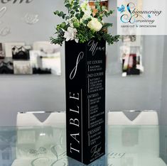 there is a tall vase with flowers in it on top of a glass tablecloth