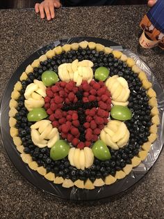 a cake with fruit arranged in the shape of a heart on top of a table