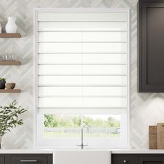 a kitchen with gray cabinets and white roman blind blinds in the window above the sink