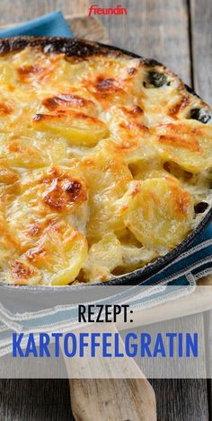 a close up of a casserole in a pan on a wooden table with the words rezept kartofelgratin