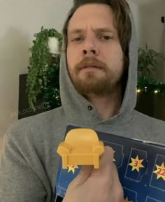 a man in a grey hoodie holding a yellow toy