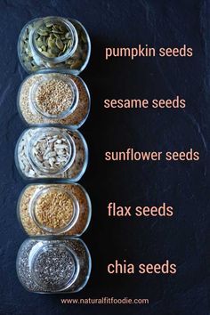 four glass bowls filled with different types of seeds on top of a black table next to each other