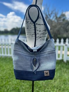 a handbag made out of old jeans is on display in front of a white picket fence