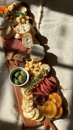 a wooden platter filled with meats, cheeses and crackers on top of a table