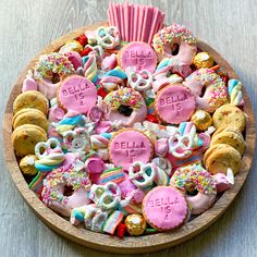 a wooden platter filled with lots of different types of cookies and pastries on top of a table