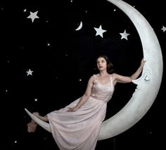 a woman is sitting on the moon with stars