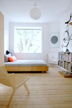 a bedroom with a bed, chair and bookshelf