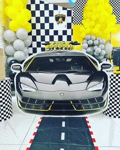 a white and black sports car on display in a room with yellow and gray balloons