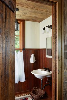 a bathroom with wood paneling and a white sink in the corner next to an open door