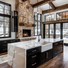 a large kitchen with black cabinets and white marble counter tops, along with an open fireplace