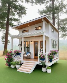 a small white house with flowers on the porch