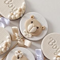 four decorated cookies with teddy bears on them and ribbons tied around the cookie toppers