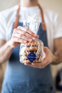 a person holding a bag of cookies in their hand and wearing an apron on the other side