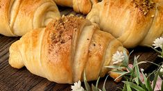 some croissants are sitting on a table with flowers and leaves around them