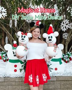 a woman standing in front of mickey mouse decorations and holding two snowman's