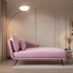 a pink chaise lounge chair sitting in a living room next to a table with a vase on it