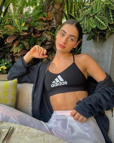 a woman sitting on top of a couch next to a plant