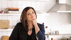 a woman sitting at a kitchen table with her hand on her chin and looking off to the side