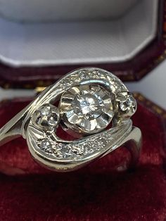 a diamond ring sitting on top of a red velvet cushion in a box with its lid open