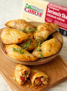 several pastries on a wooden platter next to a carton of cheddar cheese