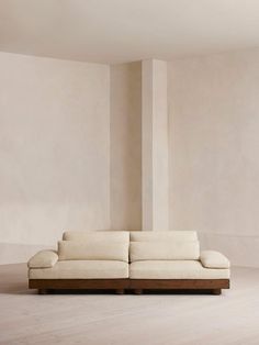 a white couch sitting in the middle of a living room next to a tall wall