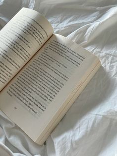 an open book sitting on top of a bed