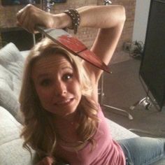 a woman sitting on top of a couch with a hat on her head and holding a remote control