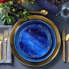 a blue and gold plate with stars on it next to silverware, napkins and flowers