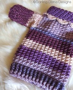 a purple and white knitted sweater laying on top of a fur rug