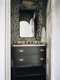 a bathroom with a mirror, sink and wallpapered walls in black and white