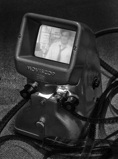 an old television sitting on top of a table next to a corded phone and plugged in