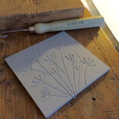 a piece of paper with flowers on it next to a carving knife and wood block