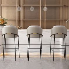 three modern bar stools in front of a marble counter