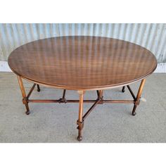 an oval wooden table with four legs and a circular top, on concrete flooring