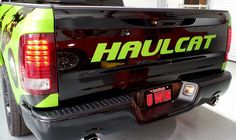 the back end of a black truck with green lettering on it's tailgate