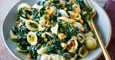 pasta with spinach and cashews in a bowl next to chopsticks