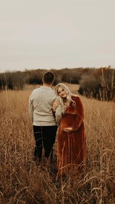 a man and woman standing in tall grass