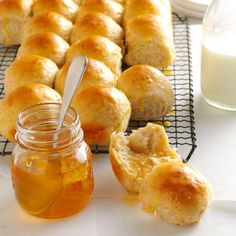 honey and rolls on a cooling rack next to a glass of milk