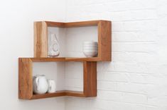 two wooden shelves on the wall with white dishes and vases in each one's compartments