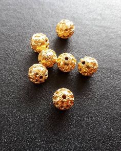 five gold bead caps on a black surface