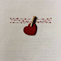 a red heart hanging from a clothes line with hearts on it's clothes pins