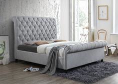 a bed that is in a room with hardwood floors and white walls, along with a rug on the floor