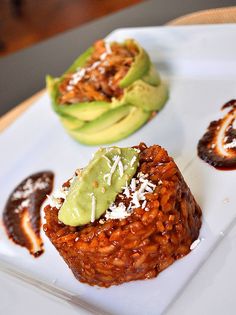 some kind of food on a white plate with avocado and other toppings