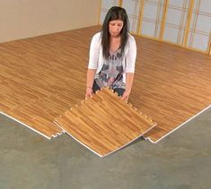 a woman sitting on top of a wooden floor next to a pile of wood planks