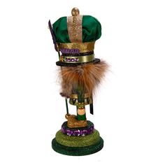 a mardi gras hat on top of a green stand with purple and gold decorations