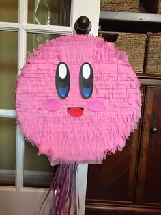 a paper plate with a face made out of pink yarn on top of a table